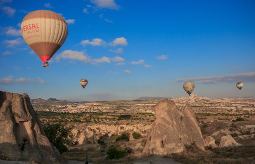 Hot air balloons soar above Cappadocia's rocky terrain during sunrise.
