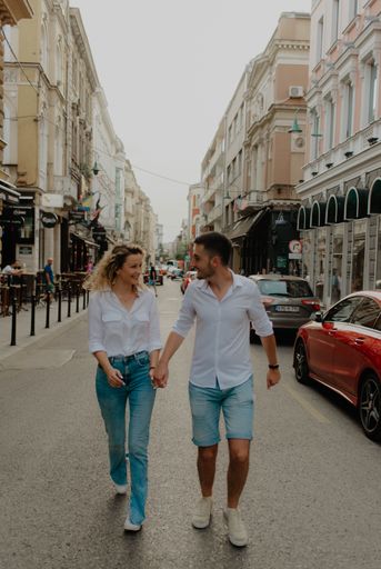 A vertical shot of a romantic couple in matching outfits walking in a city