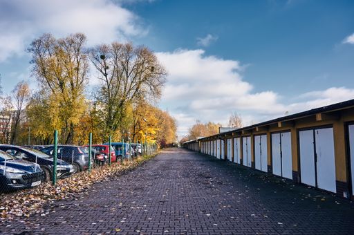 A footpath between a row of locked garage doors and a secured parking lot