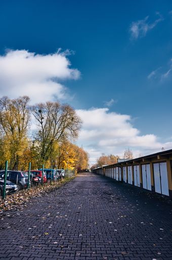 A footpath between a row of locked garage doors and a secured parking lot
