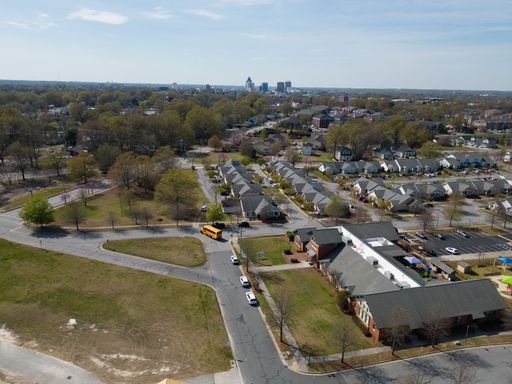 Aerial view of a suburban neighborhood with a school bus and residential houses under a clear sky in Greensboro, North Carolina.