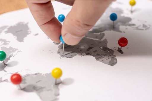 Close up of Human Hand pinning on world map. Travel destination concept