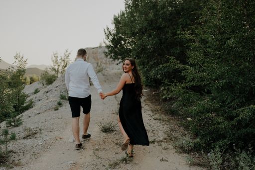 A romantic young couple holding hands and walking on a trail