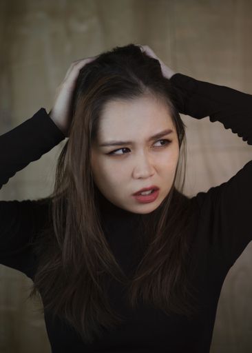 A vertical shot of a Southeast Asian girl angrily looking sidewards on a wooden background in Vietnam