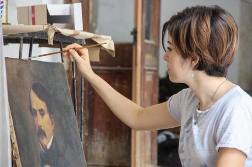 A closeup shot of a Hispanic female painting in an art studio