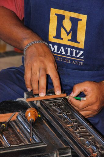 A vertical shot of a Hispanic male restoring a piece of vintage furniture