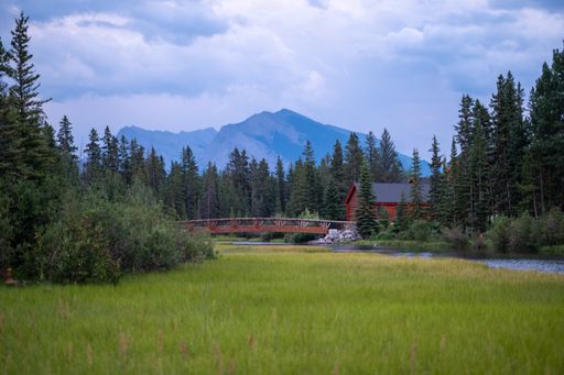 The red wooden cottage in the forest with mountains in the background.