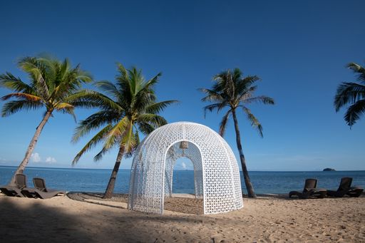 A beautiful white gazebo in the middle of the beach with palm trees