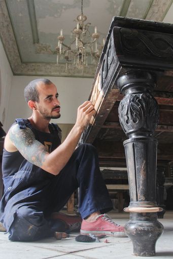 A Hispanic male restoring some vintage furniture in Cuba