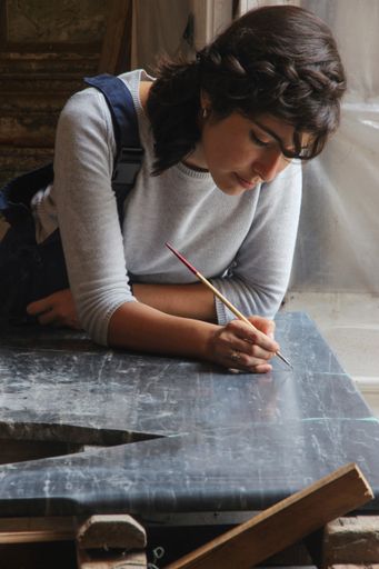 A closeup shot of a Hispanic female painting in an art studio