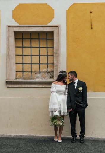 Beautiful bride and groom standing in front of yellow building at Gornji Grad in Zagreb, Croatia.
