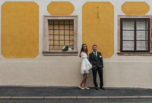 Beautiful bride and groom standing in front of yellow building at Gornji Grad in Zagreb, Croatia.