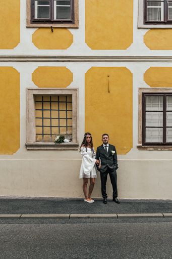 Beautiful bride and groom standing in front of yellow building at Gornji Grad in Zagreb, Croatia.