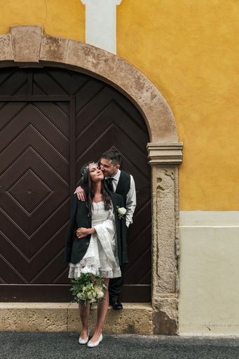 Beautiful bride and groom standing in front of wooden door on yellow building at Gornji Grad in Zagreb, Croatia.