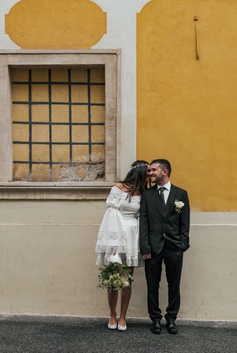 Beautiful bride and groom standing in front of yellow building at Gornji Grad in Zagreb, Croatia.