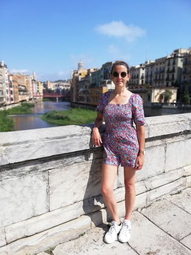 A young beautiful Caucasian female in sunglasses stands on the bridge in Girona, Spain