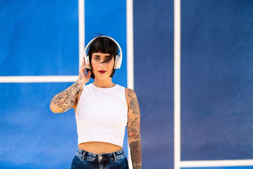 A young attractive caucasian female with tattoos listening to music with headphones and dancing