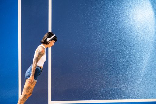A young attractive caucasian female with tattoos listening to music with headphones and dancing