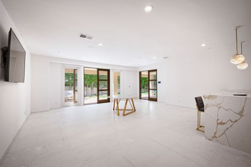 A modern living room with marble accent wall, velvet chairs, fireplace, and wall-mounted TV.