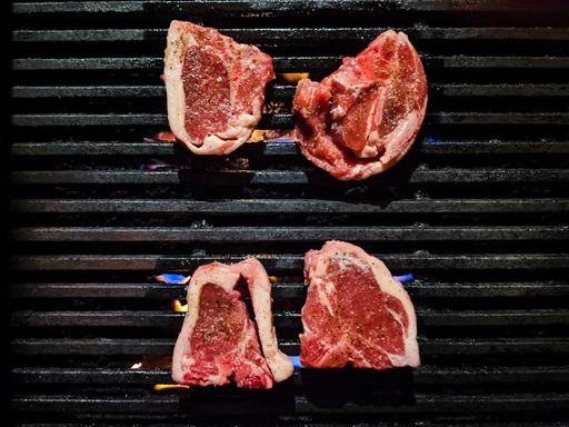 A top view of four pieces of raw meat on the grill
