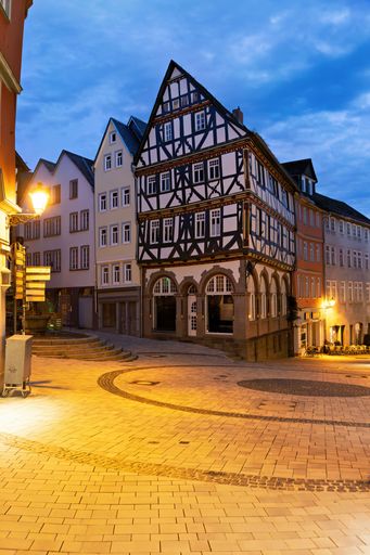 Charming half-timbered houses in a quaint German town square under evening sky, showcasing traditional architecture and cobblestone streets.