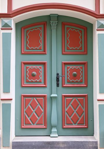 Ornate green and red vintage door with intricate patterns in a historic building.