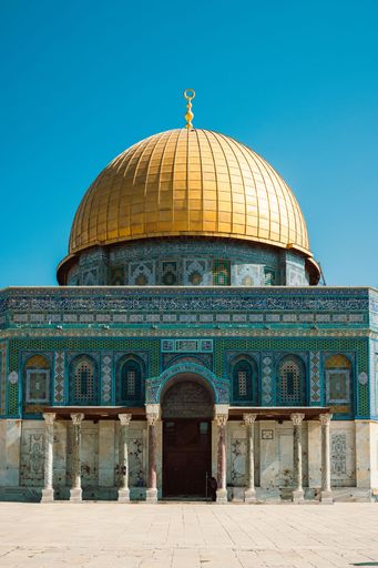 The Dome of the Rock in Jerusalem with its iconic golden dome under a clear blue sky, showcasing intricate architectural details.