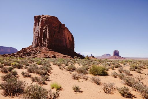 Scenic view of Monument Valley with iconic red rock formations under a clear blue sky in the desert landscape.