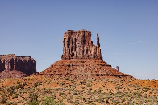 Scenic view of Monument Valley's iconic buttes under a clear blue sky, showcasing the stunning desert landscape.