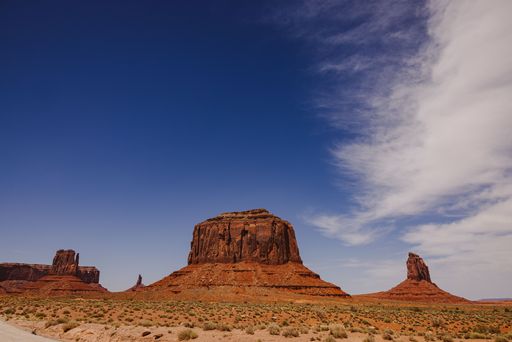 Scenic view of Monument Valley with iconic red rock formations under a clear blue sky, capturing the vast desert landscape.