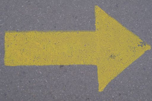 A top view of a big yellow traffic arrow right sign painted on a concrete ground outdoors
