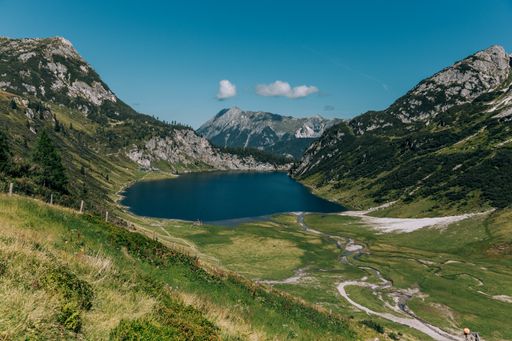 A beautiful view of a lake surrounded by the rocky green mountains