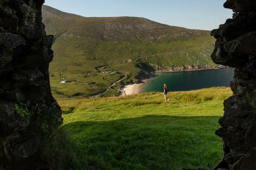A beautiful view through a window of an old building. A caucasian female traveler in Keem bay Achill Island, Ireland