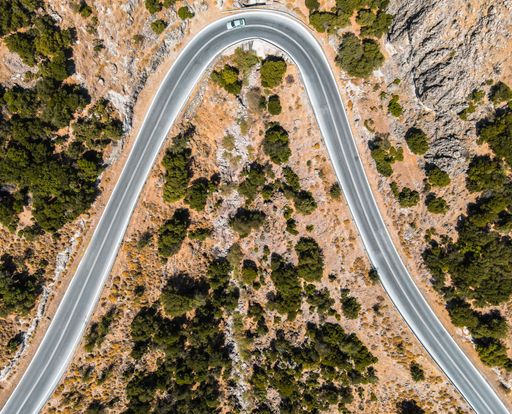 A top view of an asphalt road surrounded by trees and nature