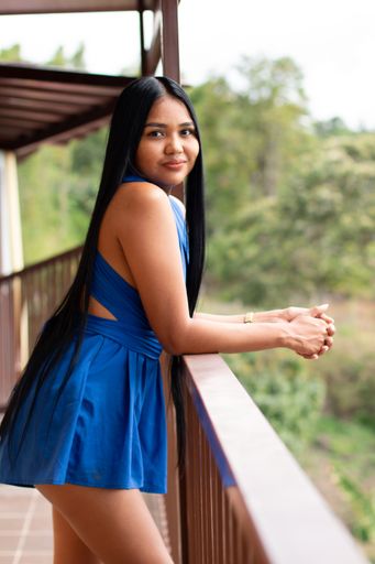 Brunette woman on a hotel balcony dressed in blue looking