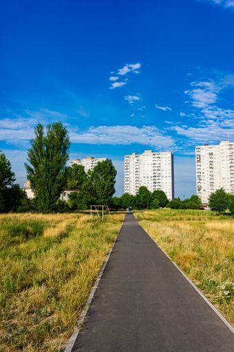 A beautiful view of a long pathway gleaming under the cloudy blue sky in the park