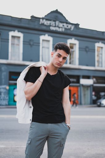 A vertical shot of a young stylish male in a black t-shirt posing on the street