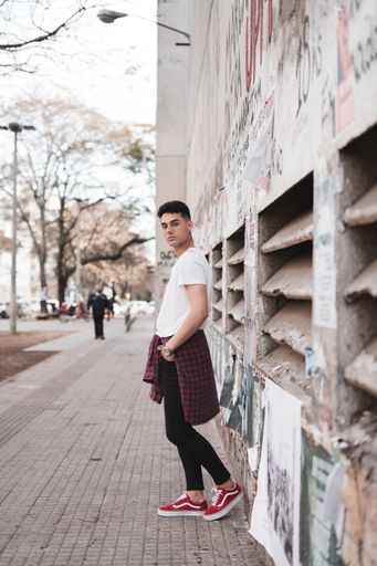 A vertical shot of a young stylish male in a white t-shirt posing on the street