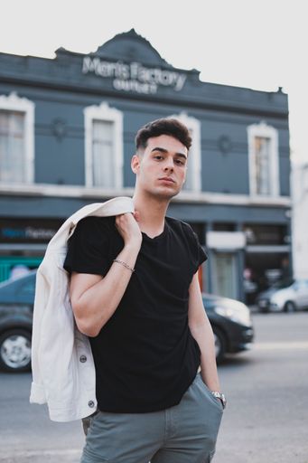 A vertical shot of a young stylish male in a black t-shirt posing on the street