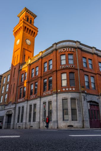 Ireland, Dublin, a low angle shot of Trinity hotel with clock tower and a man standing in front