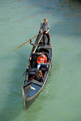 Bird's eye or drone view of a traditional Venetian Gondola with passengers on Grand Canal, Italy