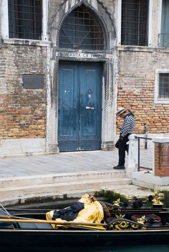 Single male Gondoliere standing in front of typical Venetian house, Italy
