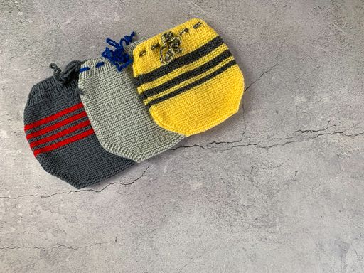 Cozy, warm colorful baby pants. Knitted clothes on a table. Handmade garment to small children. Grey background with copy space and place for text.