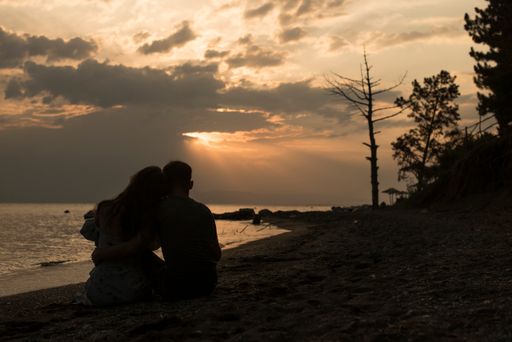 A serene view of a cute couple admiring the golden sunset on the sandy beach