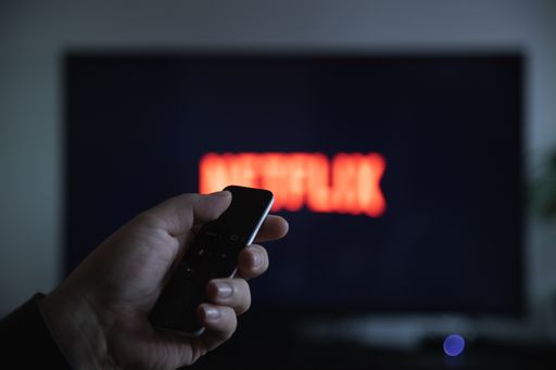 Mannheim - BW / Germany 11.17.2019: Close up of Apple TV Remote in Hand and TV Screen with Defocused Netflix Logo