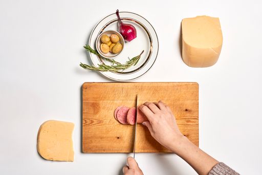 A top view of a chef making pizza with various ingredients on a white surface with a copy space