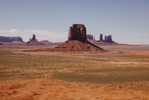 A stunning view of Monument Valley's iconic buttes under a clear blue sky, showcasing the vast desert landscape.