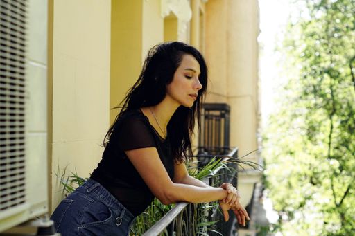 A closeup shot of a Hispanic female looking down from her balcony