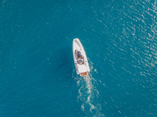 An aerial view of a motorboat sailing on the sea and making splashes