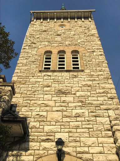 A vertical low angle shot of a beautiful stone brick tower under a clear blue sky